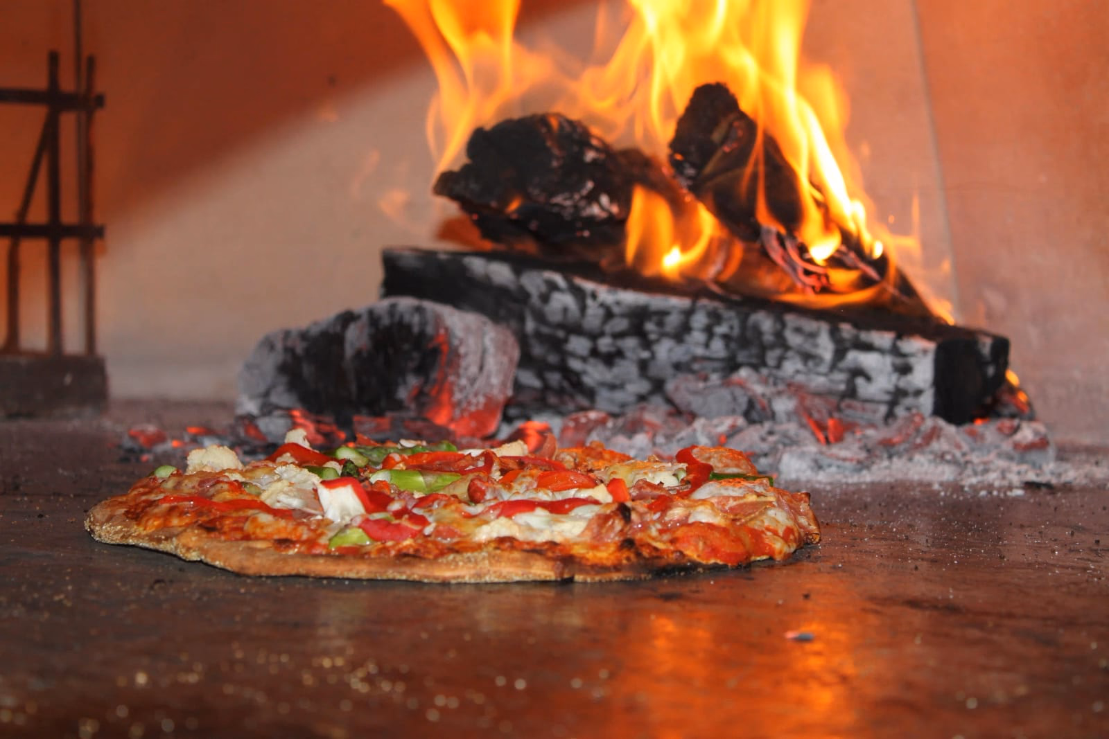 A pizza baking beside the oak fire in Santa Ana's wood-fired oven